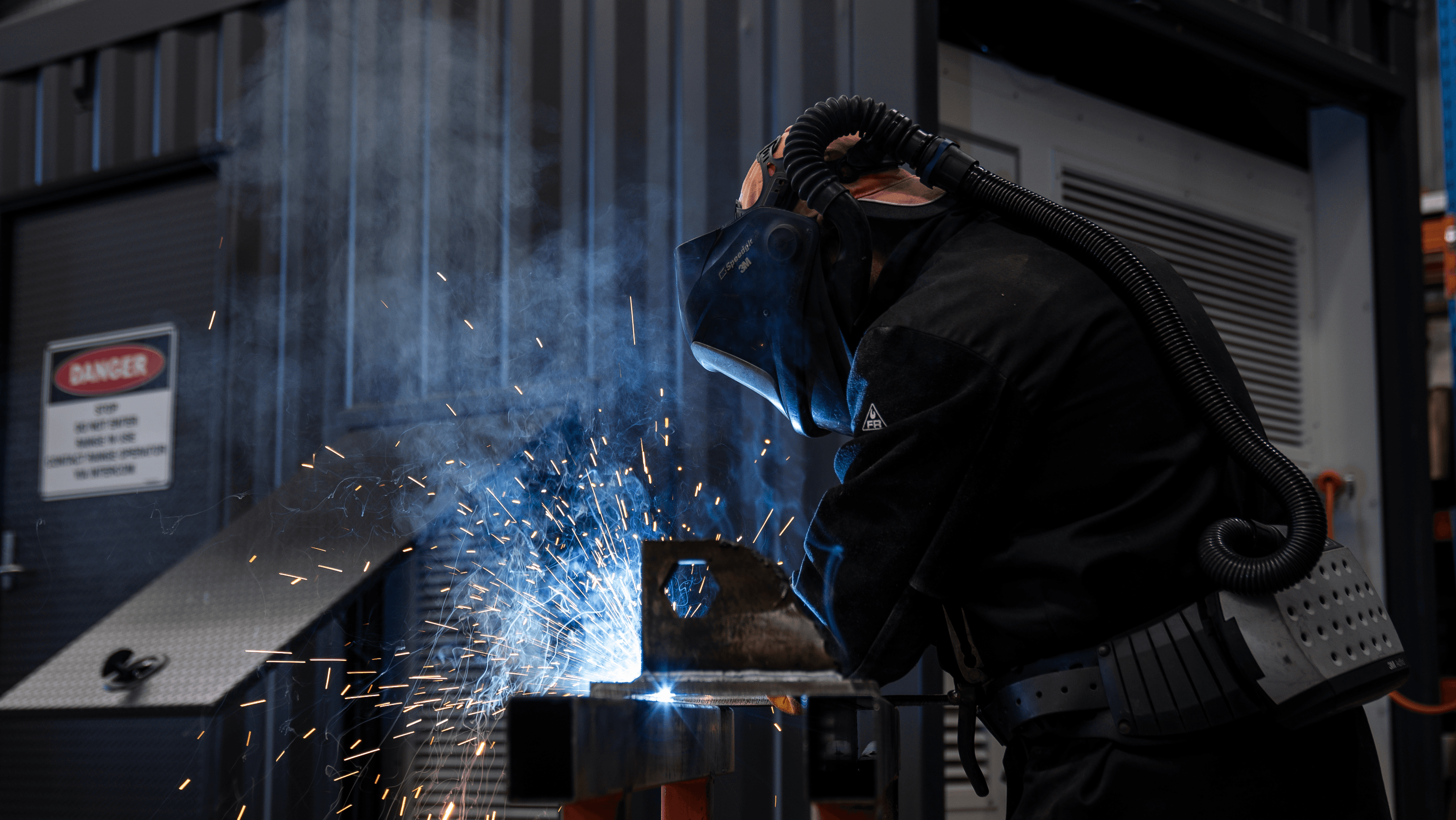 Industrial welding with bright blue sparks and protective equipment