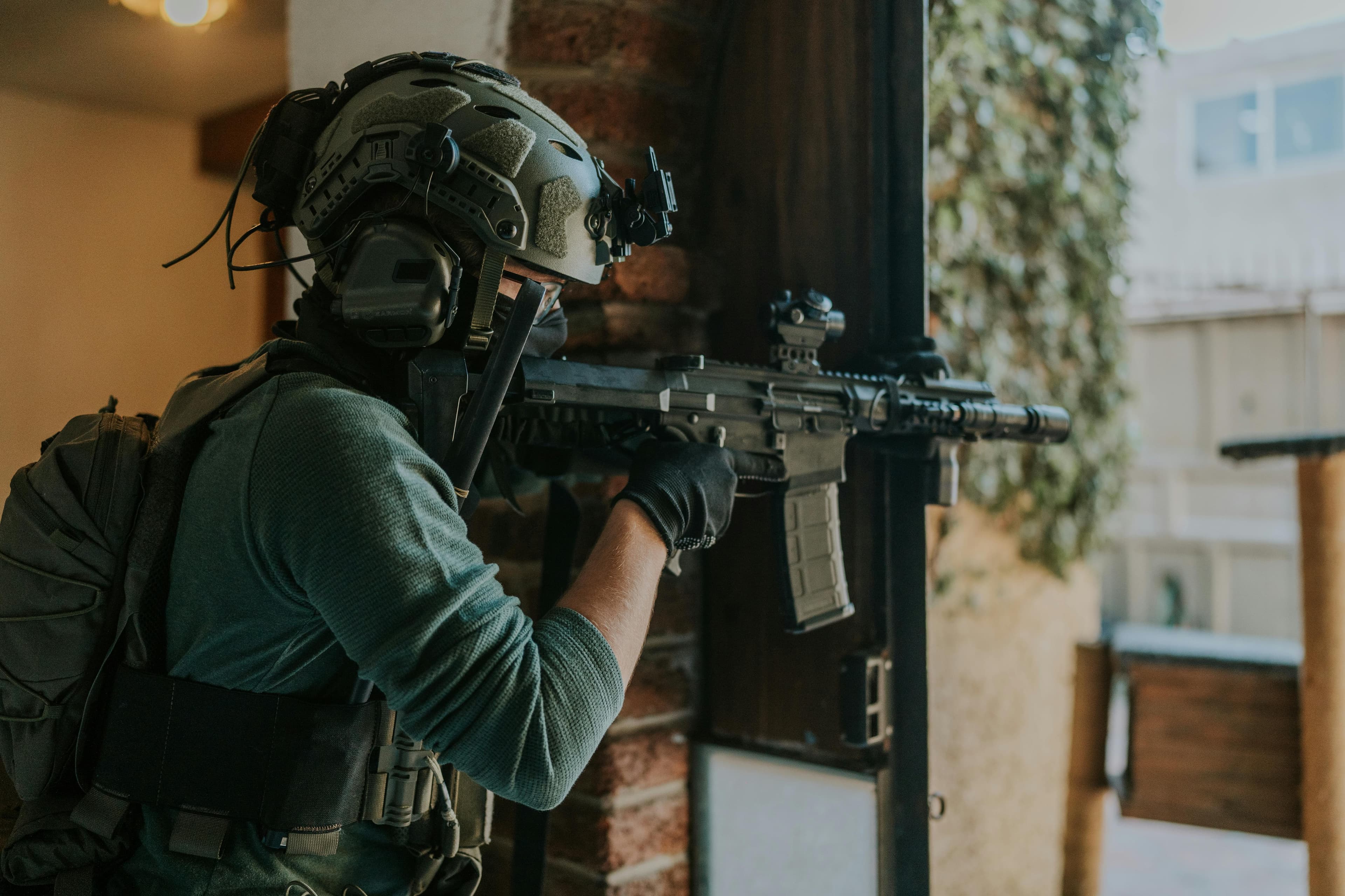 Tactical operator in combat gear aiming through window